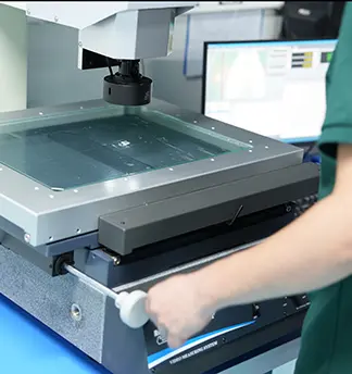 Operator using a 2D vision measuring system to verify exact dimensions of custom glass panel

